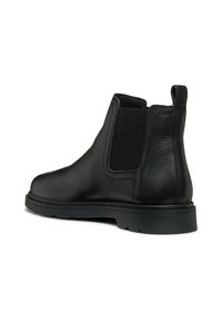 Botas Chelsea de cuero negro con paneles laterales elásticos, superficie texturizada y diseño de punta redondeada. Suela de goma con un patrón de relieve mínimo.