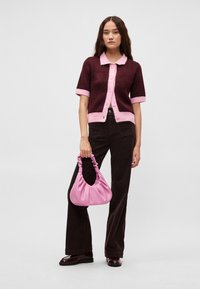 Μπορντό ζακετάκι με κοντό μανίκι, ροζ γιακά και μανσέτες, συνδυασμένο με σκούρο καφέ παντελόνι και ροζ χαλαρή τσάντα ώμου.