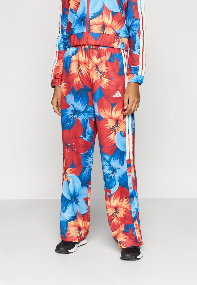 Φόρμα Adidas σε ζωντανό κόκκινο, μπλε και πορτοκαλί λουλουδάτο σχέδιο· διαθέτει ελαστική μέση, πλαϊνές ρίγες και άνετη εφαρμογή.