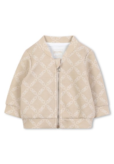 Veste zippée beige en tissu doux, avec un motif géométrique blanc répétitif et un col et des poignets côtelés. Taille 3 mois.