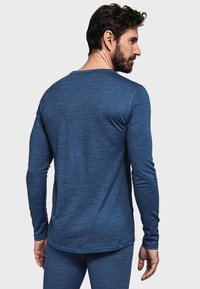 Langärmliges blaues Thermoshirt aus strukturiertem Stoff, mit Rundhalsausschnitt und geradem Schnitt. Verfügt über minimalistische Nähte und eine weiche Oberfläche.