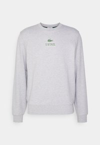 Felpa grigio con scollatura rotonda in cotone misto. Presenta il logo verde Lacoste e polsini e orlo a costine. Design semplice e senza fronzoli.