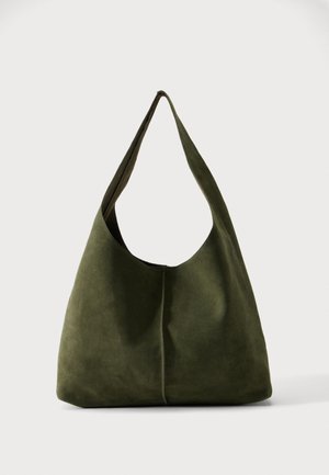 Stor, slouchy skuldertaske i olivengrønt ruskind med en bred rem og blød, ustruktureret form mod en enkel baggrund.