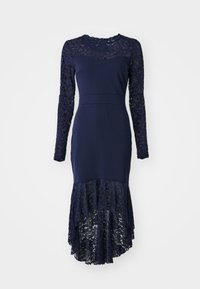 Marindress med långa spetsärmar och spetskant, med en figurnära livdel och lager av spetsdetaljer längs botten.