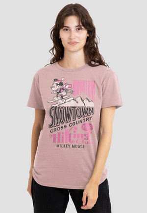 Hellrosa Baumwoll-T-Shirt mit einem Grafikmotiv eines ski fahrenden Cartoon-Charakters, mit einer fetten Schrift und retro Design-Elementen. Kurze Ärmel.