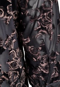 Čierna tkanina s kvetinovým vzorom ruží v tmavo ružovej a burgundskej farbe. Materiál je jemný s mierne priesvitným povrchom. Sú viditeľné dva gombíky.