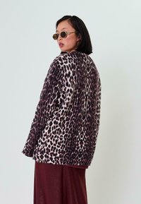 Cardigan mit Leopardenmuster aus weichem Stoff, mit lässiger Passform, langen Ärmeln und strukturiertem Finish, in den Farben Creme, Schwarz und Burgundy.