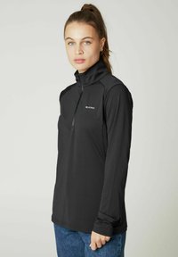 Schwarzes Langarm-Quarter-Zip-Oberteil mit hohem Kragen, weicher Textur und Kontrastnähten; mit Logo auf der linken Brust.