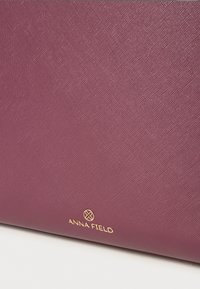 Blommefarvet tekstureret håndtaske med et subtilt mønster. Har et guld "Anna Field" logo i nederste højre hjørne.