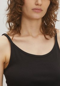 Zwarte geribbelde tanktop met een ronde halslijn en dunne bandjes, die een soepele textuur en een strakke pasvorm laat zien.