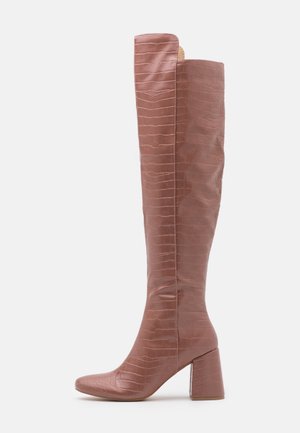 Botte haute mauve avec motif texture crocodile, talon bloc et bout pointu, vue de côté sur fond blanc.