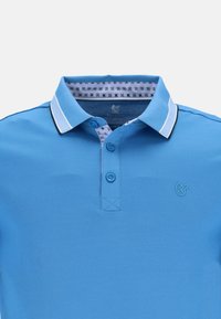 Ljusblå pikétröja i texturerad tyg, med klassisk krage, tre-knappsknäppning och kontrasterande mönstrad inre krage.