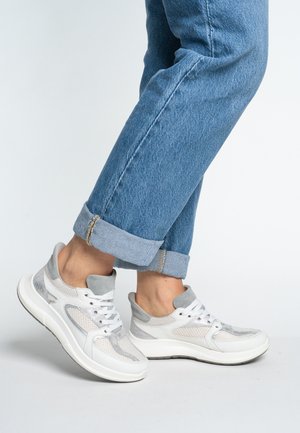 Sport sneakers in white and gray with mesh panels, rounded toe, lace-up design, and cushioned sole. Worn with cuffed blue denim jeans.