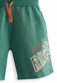 Grønne shorts med elastisk talje og orange snor. Funktioner en trykt "RAW" grafik med strålende linjer i hvid og orange.
