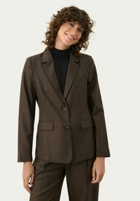 Hnědý přizpůsobený blazer z texturované látky, jednoradý s dvěma knoflíky, s klopami a postranními kapsami. Nalezený na černém roláku.