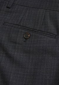 Sötétszürke kockás anyagú szabott nadrág, amelyen egy hátsó zseb látható, egyetlen fekete gombbal és felette öv hurkokkal.