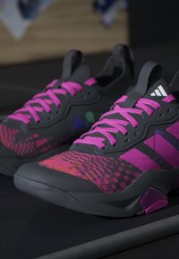 Μαύρα και ροζ αθλητικά παπούτσια Adidas με φωτεινά ροζ κορδόνια και γεωμετρικά σχέδια στην περιοχή των δαχτύλων.