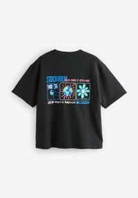 Camiseta de algodón negra con gráficos coloridos estampados en la parte trasera, incluyendo flores, un globo terráqueo y texto con detalles del evento.