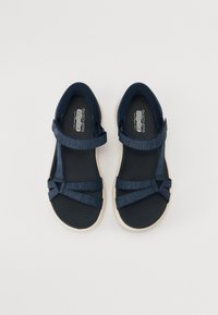 Mørkeblå sandaler med teksturerte stropper og en tykk hvit såle. Har flere festestroppene for justerbar passform. Teksturert innersåle.