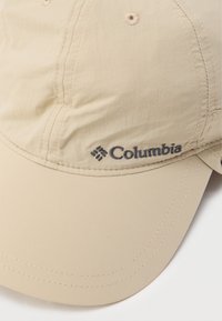 Μπεζ καπέλο μπέιζμπολ με κεντημένο λογότυπο Columbia, κατασκευασμένο από ελαφρύ ύφασμα με λεία υφή και κυρτή γείσο.