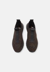 Zwarte en bruine gebreide instap schoenen met een gestructureerde bovenkant, een grote zwarte trekband en een gevoerde zwarte zool. Minimalistisch ontwerp.