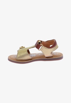 Sandalia de cuero dorado con punta y talón descubiertos, tira marrón con cierre de hebilla, suela plana, plantilla con estampado floral y texturas contrastantes.