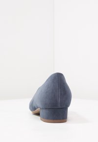 Scarpe con tacco in suede blu navy, con punta arrotondata e tacco basso a blocco. Texture liscia con finitura opaca, caratterizzate da elementi di design minimalisti.