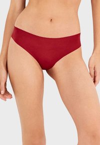 Bikini de color rojo sólido, hecho de una tela suave, con una cintura con ondas y un diseño minimalista, sin patrones o acentos visibles.