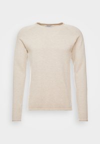 Chemise beige à manches longues et col rond en tissu texturé. Comprend un col et des poignets côtelés avec une petite étiquette sur l'ourlet inférieur.