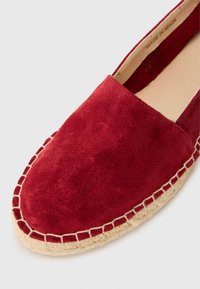 Crvene suede espadrile s okruglim vrhom, bež užadnim đonom i остављеним detaljima duž ruba. Proizvedeno u Španiji.