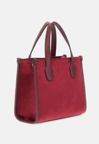 Grimizna torbica s glatkom, blago teksturiranom površinom, dualnim gornjim ručkama i strukturnim dizajnom bez vidljivih metalnih dijelova.