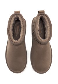 Botines de ante marrón con un suave interior acolchado, punta redondeada y paneles laterales elásticos para facilitar el uso.
