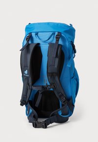 Blue backpack with adjustable navy straps, padded back panel, and side pockets. Smooth fabric with buckles and a top handle for carrying.