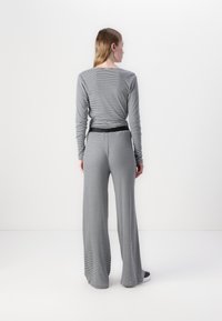 Haut à rayures à manches longues et pantalon évasé en gris et noir, avec une taille ajustée, une texture lisse et une coupe décontractée.