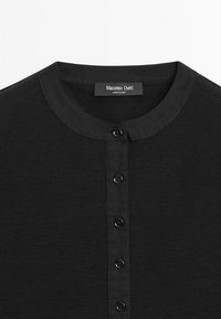 Chemise noire à boutons avec col rond et courte patte de boutonnage, ornée d'une étiquette Massimo Dutti au niveau du col.