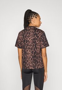 Tamsios rudos ir juodos spalvos marškinėliai su leopardų raštu, trumpomis rankovėmis, apvalia iškirpte, laisvo silueto. Dėvimi su juodomis tamprėmis, kurios turi tinklinį intarpą.