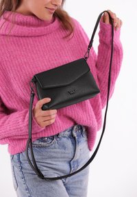 Černá crossbody taška vyrobená z texturovaného materiálu, s klopovým zavíráním, nastavitelným popruhem a malým logem na přední straně.