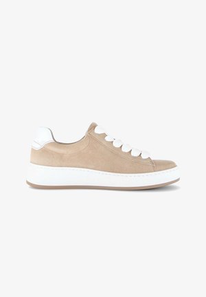 Beige suède sneaker met dikke witte zool, witte hielkap en dikke witte veters, zijaanzicht op een witte achtergrond.