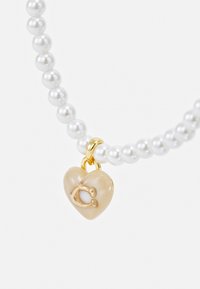 White pearl necklace with a beige heart charm featuring a gold accent. The charm has a small decorative element in the center.
