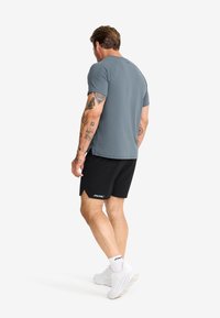 Light blue athletic t-shirt with short sleeves paired with black shorts. Simple design with a logo detail on the shorts.