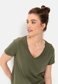 Olijfgroene T-shirt met korte mouwen en V-hals. Gemaakt van zachte stof, met een ontspannen pasvorm en een gladde textuur zonder zichtbare patronen.