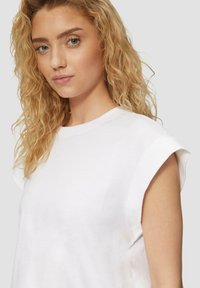 Witte katoenen t-shirt met opgerolde korte mouwen, ronde halslijn en een comfortabele pasvorm; gladde textuur en minimale ontwerpelementen.