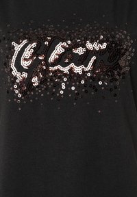 Schwarzes T-Shirt mit einem paillettenbesetzten "Glam"-Design in Silber- und Rosatönen, das eine strukturierte, funkelnde Oberfläche mit einer Mischung aus großen und kleinen Pailletten aufweist.