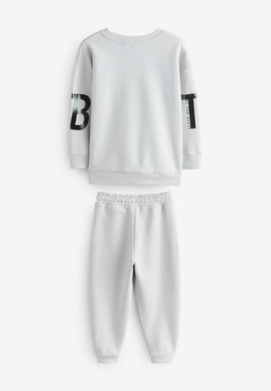 Grau Baumwoll-Zweiteiler bestehend aus einem langärmeligen Sweatshirt mit schwarfer Grafik auf dem Ärmel und passend tapered Hosen mit einem elastischen Bund.