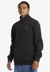 Fleeceová mikina v tmavom antracitovo sivej farbe s vysokým golierom, štvrťzip zavretím a prednou vreckom, s rebrovanými manžetami a spodným lemom.