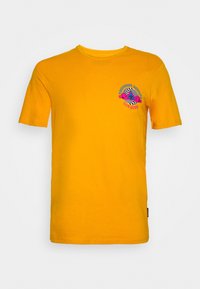 Žluté bavlněné tričko s krátkým rukávem, na levé straně hrudi s barevným grafickým potiskem. Kulatý výstřih, volný střih.