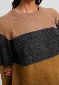 Knit sweater with horizontal stripes in light brown, dark gray, and mustard yellow. Soft texture and ribbed neckline; warm appearance.