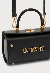 Μαύρη δερμάτινη τσάντα χειρός με δομημένο σχήμα, διαθέτει πάνω λαβή, ρυθμιζόμενο λουρί ώμου και μεταλλικά στοιχεία σε χρυσό τόνο. Το λογότυπο "LOVE MOSCHINO" εμφανίζεται έντονα.