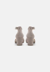 Scarpe alte grigie in suede con punta arrotondata, cinturino alla caviglia e tacco a blocco. La superficie è morbida e con finitura opaca.