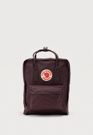 Mochila de poliéster granate con un logo redondo prominente, asa superior y bolsillo frontal con cremallera. Forma rectangular con correas de hombro ajustables.